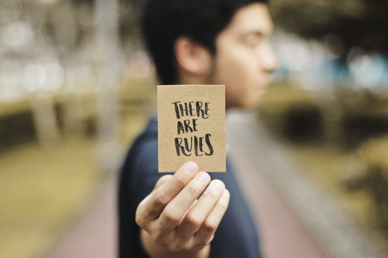 Man holding card saying "There are Rules"